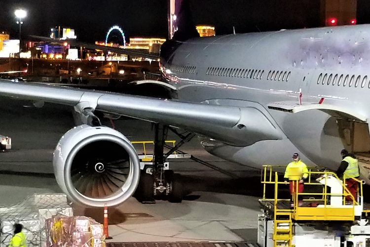 at-the-airport-cargo-handlers-on-the-tarmac-loading-cargo-pallets-of-supplies-into-the-cargo-hold-of_t20_xvgWx8